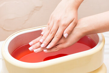 The process of paraffin therapy of a female hand is shot close up in a beauty salon.