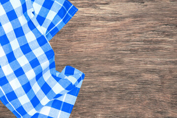 Topview of blue checkered kitchen cloth, textile, tablecloth or napkin on a empty rustic wooden table. Template for food and product display montage. Macro.