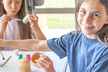 A child paints a wooden blank of a nesting doll. Children's crafts