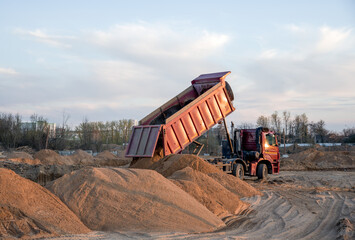 Wall Mural - Dump truck unloading earth sand for road construction or for foundation work.