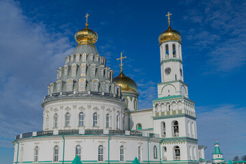 Wall Mural - New Jerusalem orthodox monastery domes and bell tower, with some snow and golden crosses, with sunset light, blue sky and white clouds, Istra, Russia