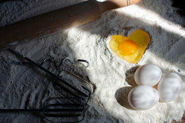 egg is broken into flour in the shape of a heart. cookie making process