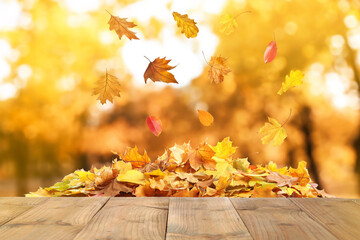 wooden surface and falling autumn leaves outdoors