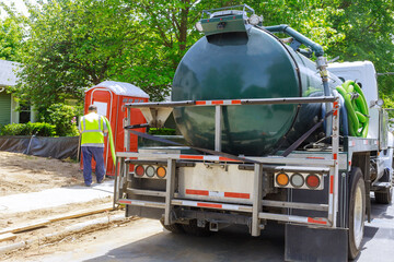 Sewage truck on worker pumping feces out of rental toilet for disposal and cleaning