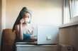 © Strelciuc - Lovely caucasian woman drinking milk with cereals after a shower while sitting at the computer