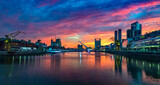 Fototapeta Londyn - Puerto Madero Bridge and city by the river, during sunrise, with colorful clouds. 