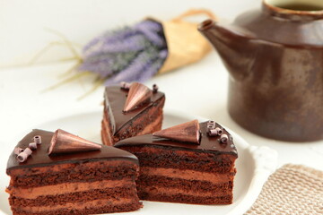 Wall Mural - Chocolate cake slice with curl on white background. cake with whipped cream and mascarpone filling. Delicious naked cake filled with cream, topped with chocolate and decorated with flowers,