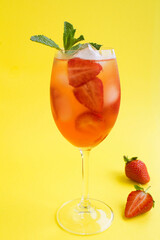 Wall Mural - Cocktail drink with strawberry and ice in a wineglass on the yellow  background. Location vertical. Closeup.