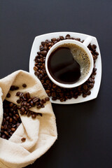 coffee beans in a bag with a white Cup of fresh coffee on a black background. space for text, top view.