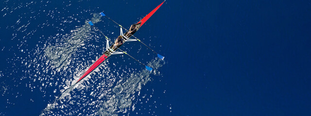 Aerial drone top ultra wide panoramic view of sport canoe rowing synchronous female athletes competing in deep blue sea