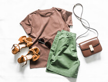 Women's Summer Clothing-brown T-shirt, Cotton Green Shorts, Suede Sandals, Cross Body Bag On A Light Background, Top View. Fashion Beauty Concept