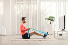 Man Exercising With An Elastic Band In Front Of A Tv