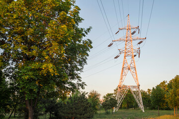 High voltage towers with electrical wires on dark cloudy sky background. Electricity transmission lines, electric power station