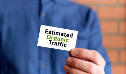 A man in a blue shirt holds a sign with the text of Estimated Organic traffic in one hand