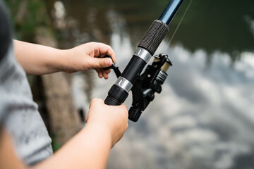 Fisherman with rod, spinning reel on the river bank. Sunrise. Fishing for pike, perch, carp. Fog against the backdrop of lake. background Misty morning. wild nature. The concept of a rural getaway.