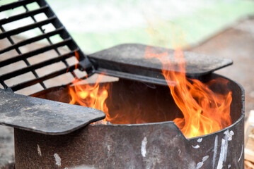 Fire in black metal pit with grate at campsite