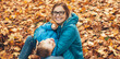 © Strelciuc - Blonde caucasian mother with eyeglasses dressed in blue clothes and her son playing on the ground with leaves