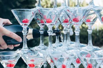 Wall Mural - pyramid of champagne glasses at an outdoor celebration. A glass of champagne with a cherry.