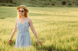 © Stanislav - A girl in a straw hat walks on a green field at sunset. Blonde in nature on a summer day. Summer holidays.