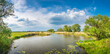Panoramic over forests, lake with a fishman and rasp yellow field near Magdeburg at late Spring, Germany, sunny day