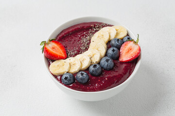 Blueberry smoothie, banana, chia seeds, fresh strawberries in bowl. Eating healthy breakfast bowl. Clean eating, dieting, detox, vegetarian, vegan food concept.