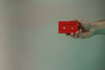 Poster - Hand holding red audio cassette tape in the color light. Beautiful minimal in neon light. Minimalism retro style concept. Background pattern for design.