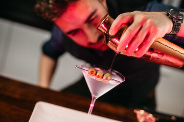 Wall Mural - Portrait of caucasian bartender preparing dry martini, elegant and classic alcoholic cocktail drink