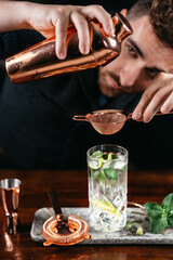 Wall Mural - barman preparing and pouring gin cocktail. mojito cocktail drink with bar background.