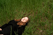 © Maxim - a girl in a black sweatshirt lies in a meadow enjoying calm with closed eyes, view from the top