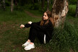 © Maxim - a girl in a black sweatshirt sits by a tree thinking about who she wants to be in the future
