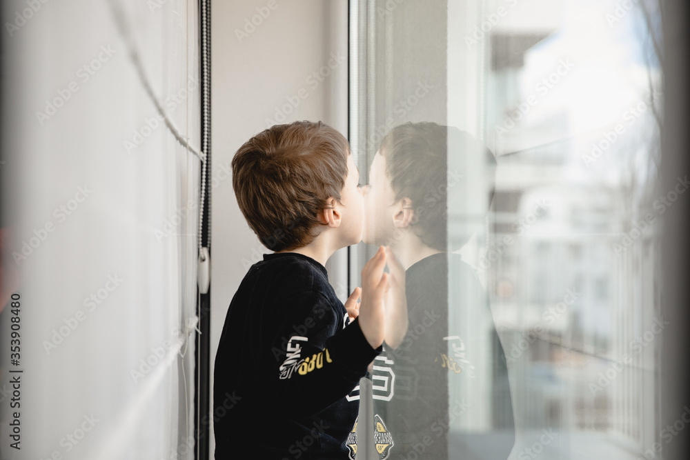 Dziecko, mały chłopiec wyglądający przez szybę, okno  - obrazy, fototapety, plakaty 