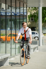 Canvas Print - Contemporary young businessman riding bicycle on sunny summer day