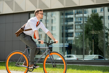 Canvas Print - Young businessman sitting on bicycle and moving to appointment with client