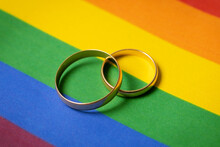 Same-sex Marriage Concept - Two Wedding Rings On Lgbt Rainbow Flag