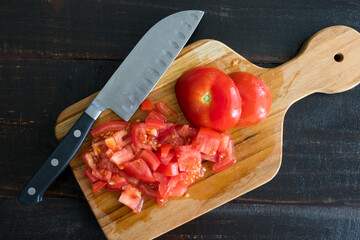 Wall Mural - Chopping a Tomato on a Cutting Board: Finely chopping or dicing a fresh tomato on a wooden cutting board