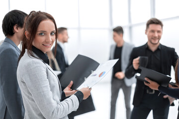 smiling business woman with clipboard standing in a modern office