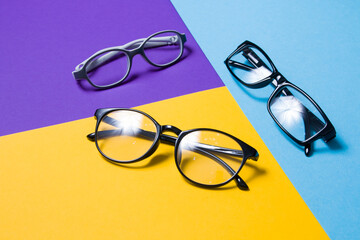 Sticker - several pairs of glasses lie on a colored background, glasses for adults and children, top view, cop