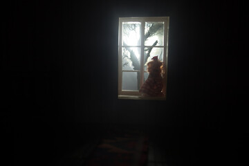 Old creepy eerie baby crib near window in dark room. Scary baby silhouette in dark. A realistic dollhouse living room with furniture and window at night