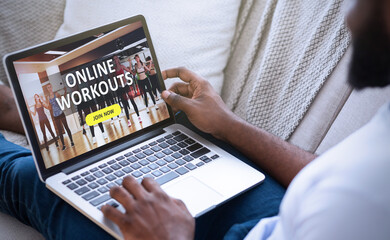 Black man watching sport training online on laptop