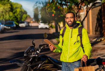 Portrait of delivery man with his motorcycle with delivery. Parcel delivery concept.