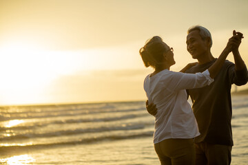 Romantic senior couple dancing together on beach at dusk sunset..Retirement age concept and love, copy space for text