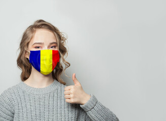 Wall Mural - Happy woman in face mask holding thumb up with national Romania  flag background. Flu epidemic and virus protection concept