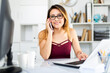 © JackF - Latina woman using phone at office