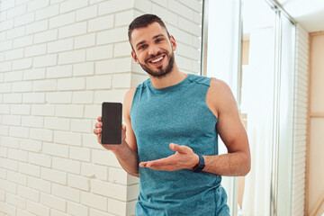 Wall Mural - Handsome young man holding cellphone and smiling