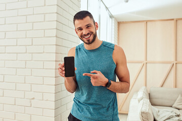 Poster - Cheerful young man pointing finger at mobile phone