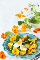 Poster - salad with nasturtium leaves and flowers of the plant. bright summer salad with edible  flowers and yellow tomatoes with egg, sunflower seeds.