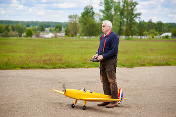 Wall Mural - A man launches a radio-controlled aircraft on the runway in the spring.