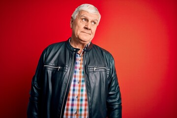 Wall Mural - Senior handsome hoary man wearing casual shirt and jacket over isolated red background smiling looking to the side and staring away thinking.
