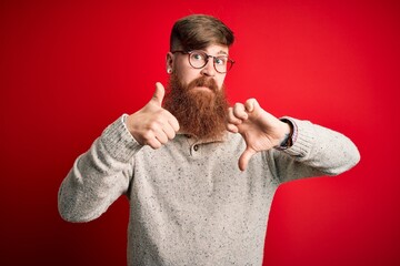 Poster - Handsome Irish redhead man with beard wearing casual sweater and glasses over red background Doing thumbs up and down, disagreement and agreement expression. Crazy conflict