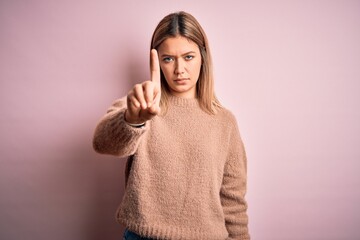 Sticker - Young beautiful blonde woman wearing winter wool sweater over pink isolated background Pointing with finger up and angry expression, showing no gesture